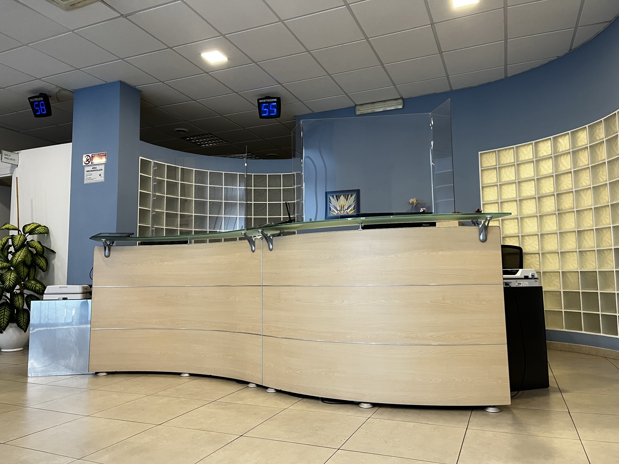 Banco dell'accettazione del laboratorio De Vitis, con schermo numeratore e pareti blu della sede